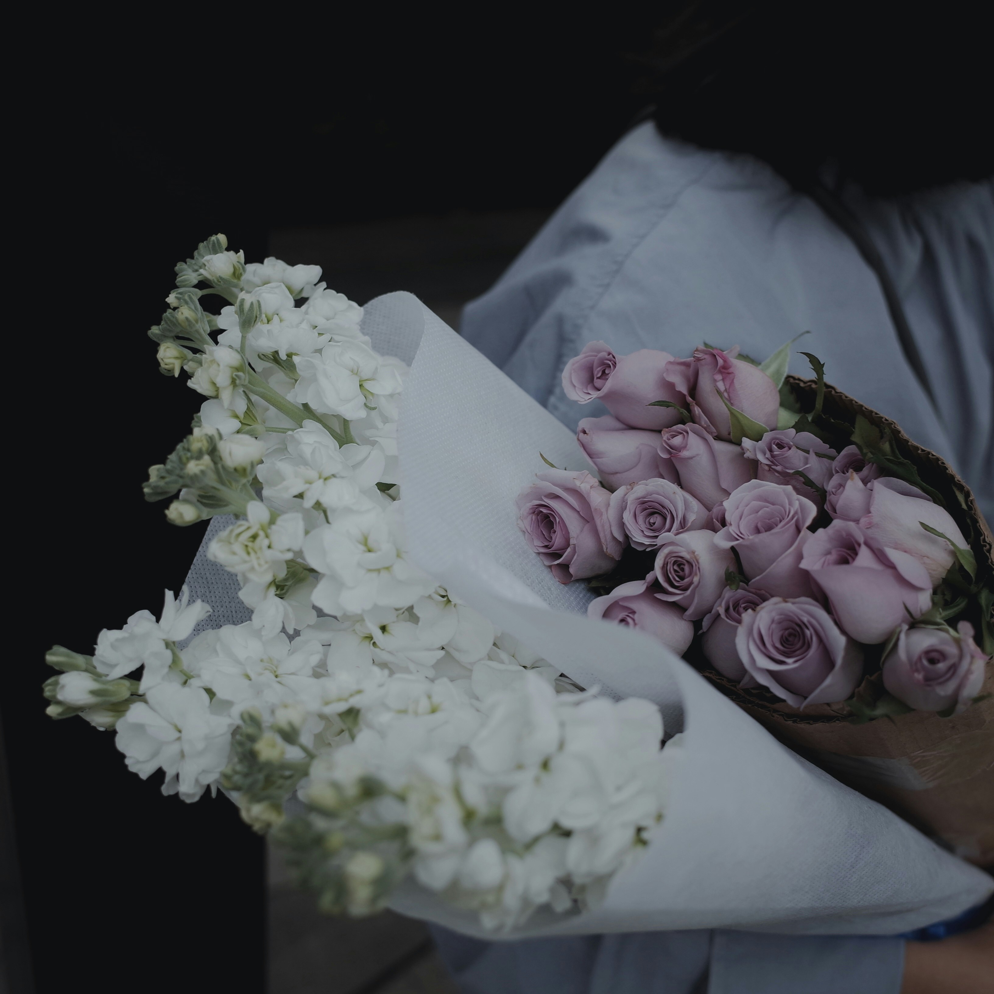 person holding purple and white flower bouquet